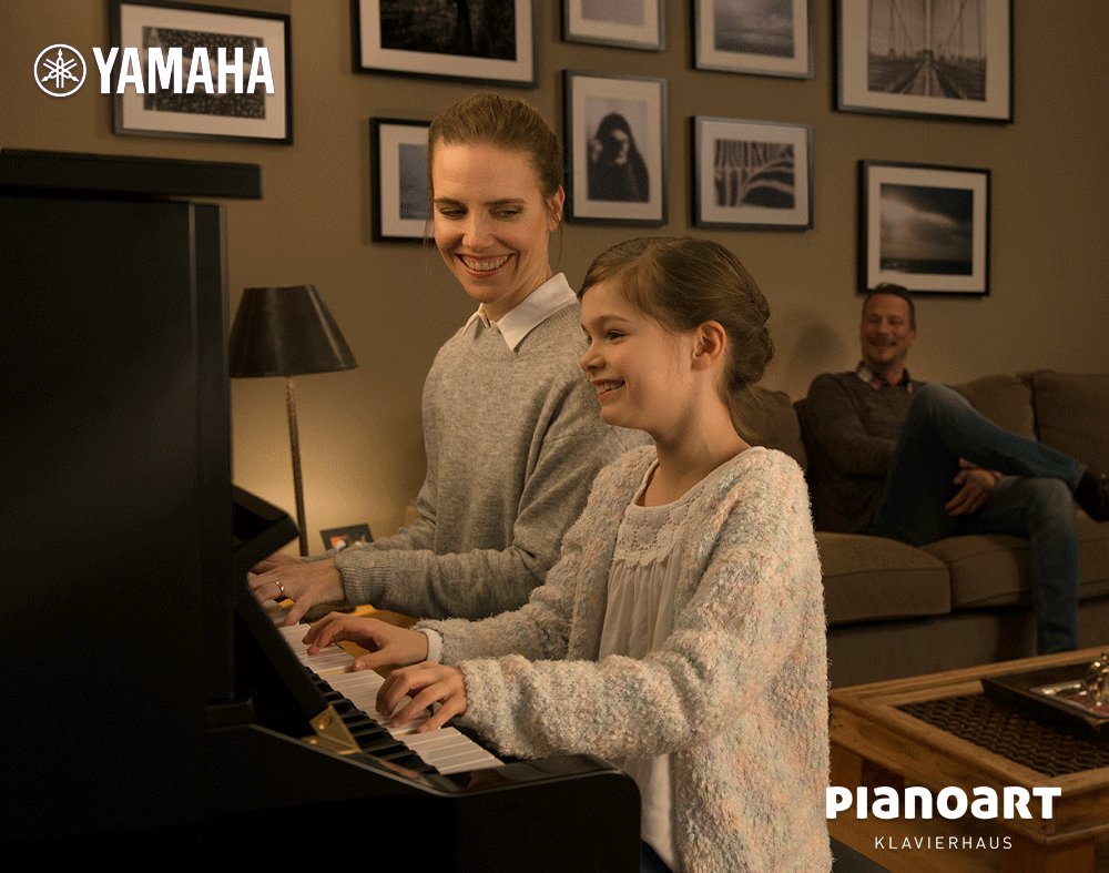 Mädchen spielt mit Mutter auf Yamaha TransAcoustic Klavier und Vater hört zu