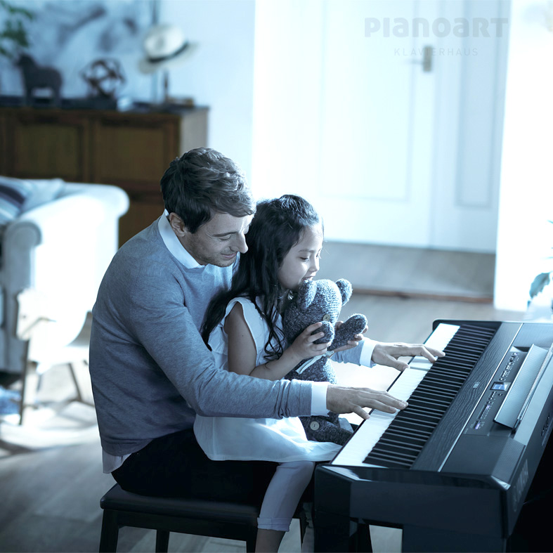 Ein Mann spielt mit seiner Tochter auf einem Yamaha P-525 Digitalpiano